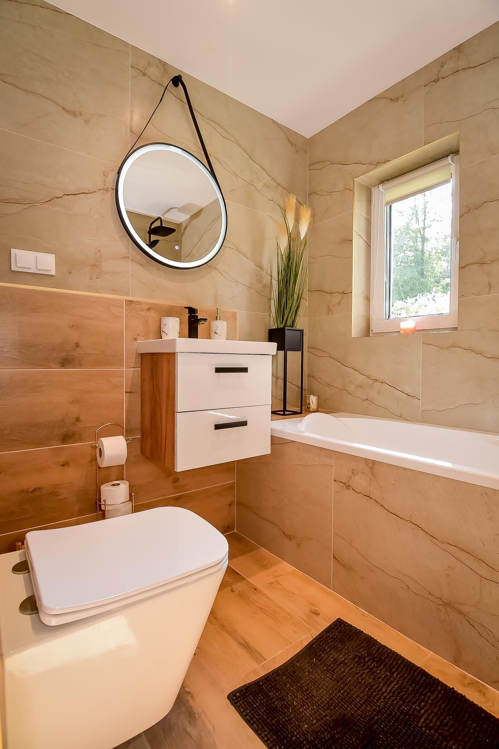 A modern bathroom with a white toilet, a vanity with a mirror, and a bathtub.
