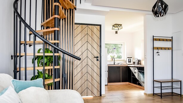 A modern interior with a spiral staircase, a kitchen area, and a seating area with cushions. - Domki Perła Białki z Jacuzzi (Bukowina Tatrzanska)