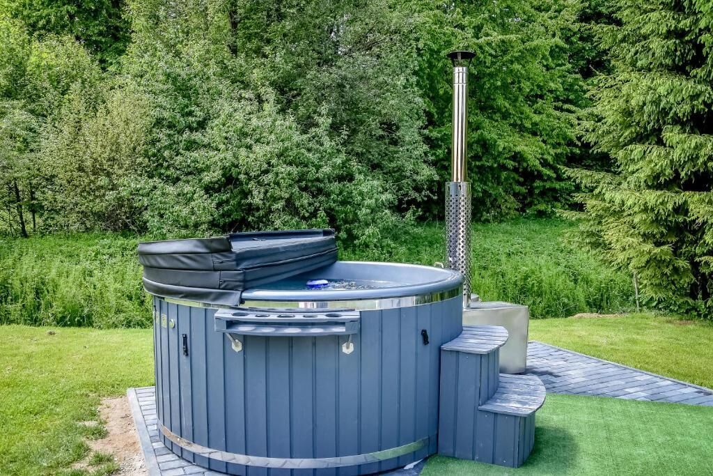 Un bain à remous doté d’une cheminée, entouré d’une terrasse en briques et d’une végétation luxuriante.