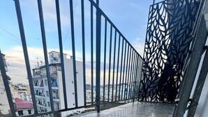 A balcony with a tiled floor and metal railings, overlooking a cityscape with buildings. - Urban Oasis in Algiers' Heart (Sidi M'Hamed)