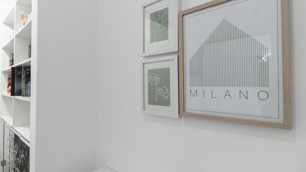 Un mur décoratif composé de tableaux encadrés, dont l’un présente le mot « MILANO ».