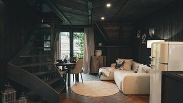Un interior rústico con una escalera de madera, un comedor, un sofá y un refrigerador.