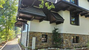 Una casa de dos pisos con cimientos de piedra, vigas de madera y múltiples ventanas.