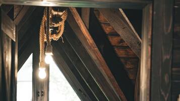 Une pièce mansardée avec un plafond en pente, une porte en bois, un radiateur et une ampoule suspendue.
