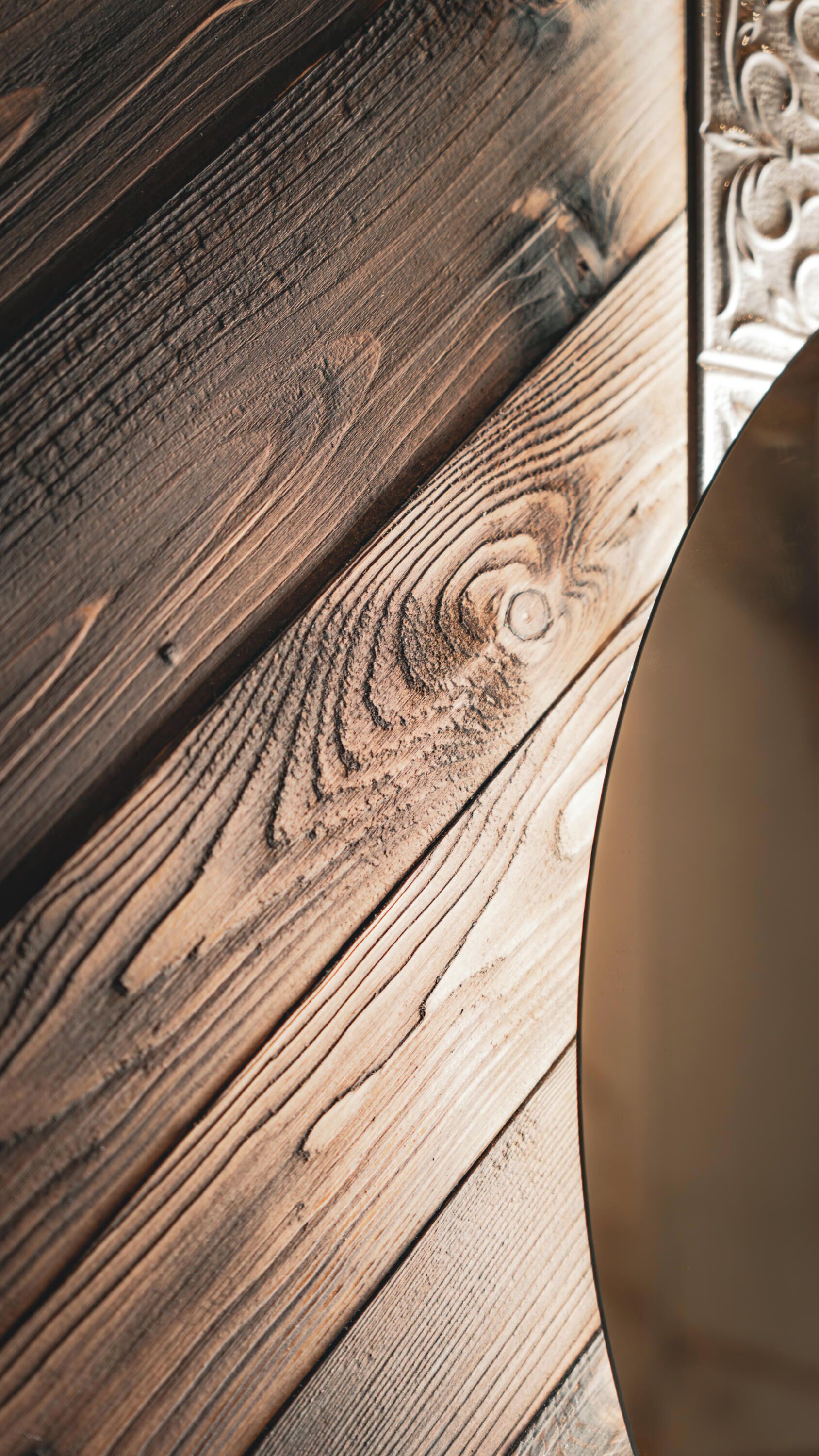 A close-up of a wooden surface with visible grain patterns and a circular object partially visible.