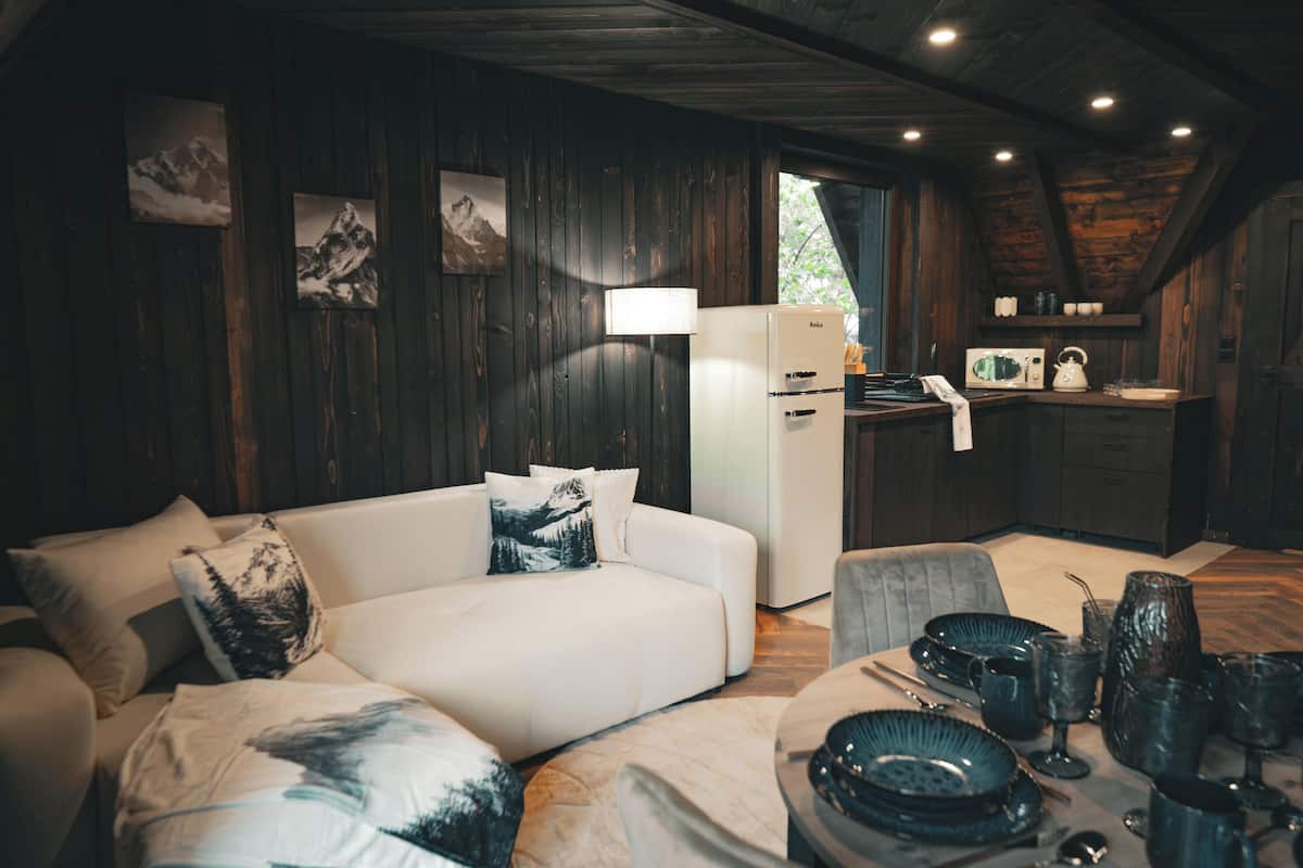 Ein gemütliches Blockhauss-Interieur mit Sofa, Esstisch und Küchenzeile.