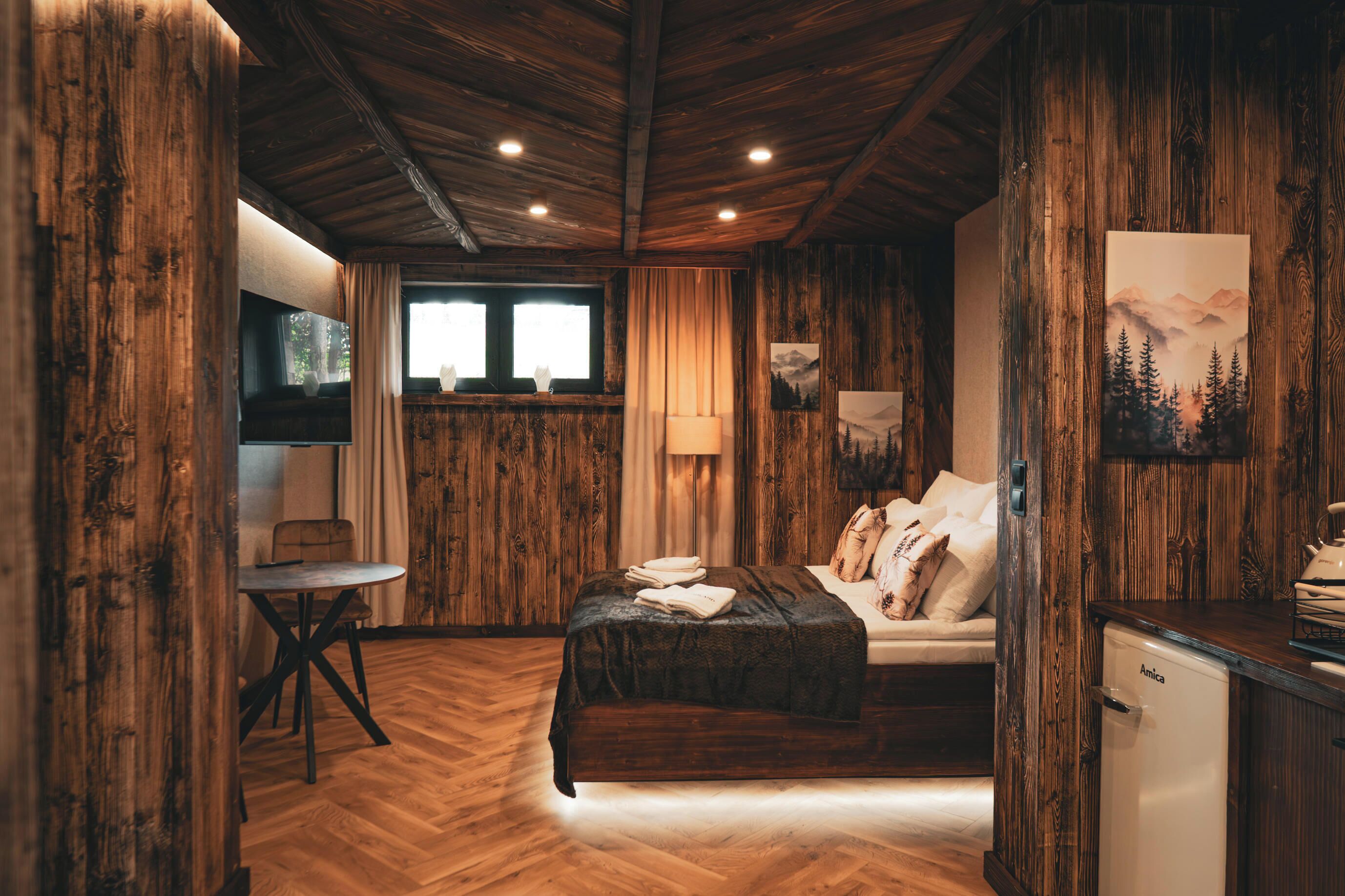 Habitación con detalles de madera, una cama, un escritorio y un refrigerador.