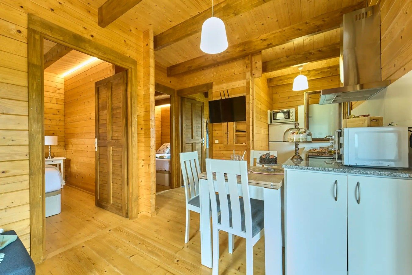 A wooden interior with a dining area, a kitchen with a microwave, and a television.
