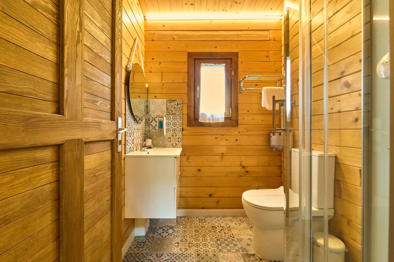 Ein kleines Badezimmer aus Holz mit Toilette, Waschbecken und Duschbereich.