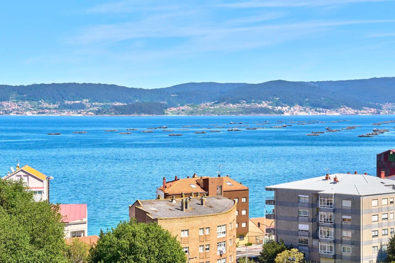 Un paisaje urbano costero con edificios, un mar azul cristalino y barcos.