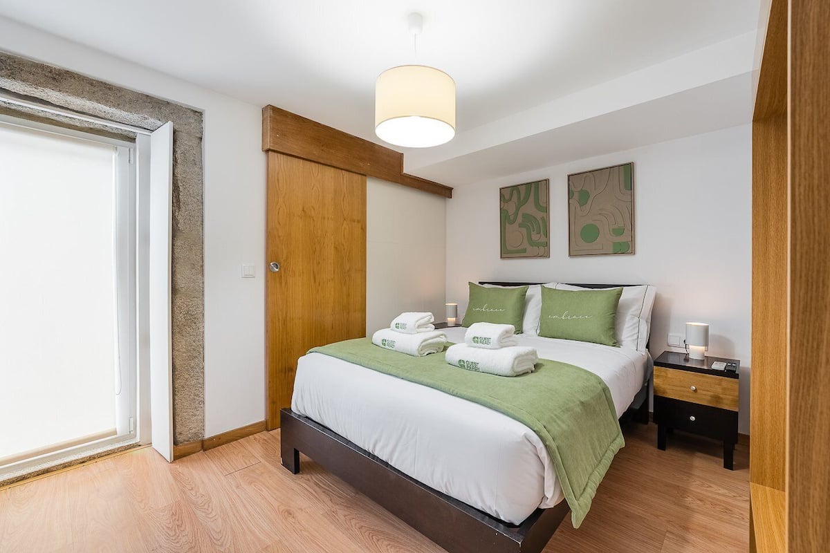 Une chambre bien rangée, avec un lit, des tables de chevet, une armoire et des œuvres d’art accrochées au mur.