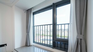A room with a large window, a balcony, and a view of a cityscape. - Tyms Hongqiao Deluxe 3BR 2BA APT  (Shanghai)