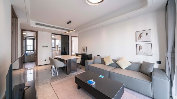 A modern living room with a sofa, coffee table, and a dining area with chairs and a table. - Tyms Hongqiao Deluxe 3BR 2BA APT  (Shanghai)