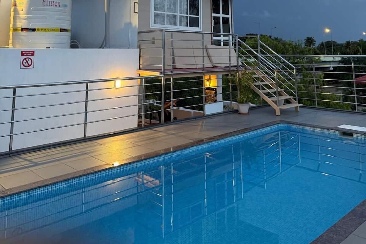 Un espace aménagé au bord de la piscine, comprenant un poste de surveillance pour les sauveteurs, une piscine et un escalier menant à une terrasse.