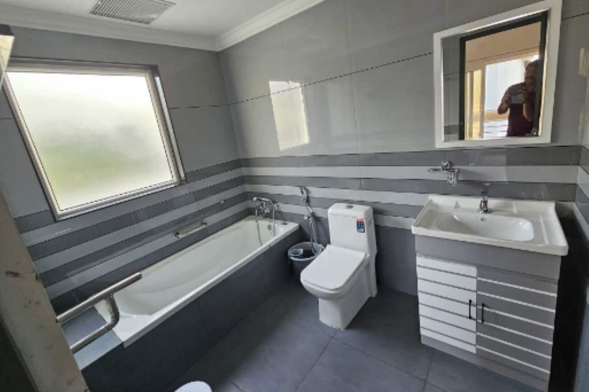 Une salle de bain équipée d’une baignoire, de toilettes et d’un lavabo, avec des murs à rayures et une fenêtre.