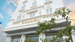 Un edificio blanco con el nombre "GOLDEN" exhibido destacadamente en la fachada.