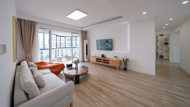 Een moderne woonkamer met een bank, salontafel, televisie en houten vloer.