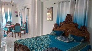 Un dormitorio amplio con una cama grande, una zona de comedor con sillas y un ventilador de techo.