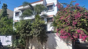 Un edificio de varios pisos con fachada blanca y tejado de tejas rojas.