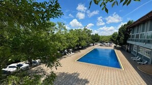A swimming pool with lounge chairs, a covered area, and a building with large windows. - Skyview Resort Buriram (Buri Ram)