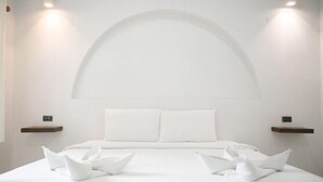 Ein modernes Hotelzimmer mit einem großen Bett, weißen Laken und einem einzigartigen, gewölbten Deckenstil.