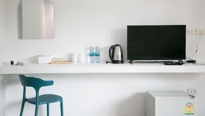 A white wall with a large mirror, a flat-screen TV, a kettle, and a small refrigerator. - Skyview Resort Buriram (Buri Ram)