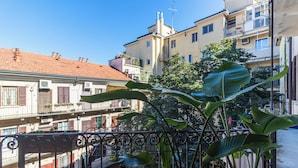 A residential building with balconies, a red-tiled roof, and a large plant in the foreground. - Italianway - Bezzecca 12 (Milan)