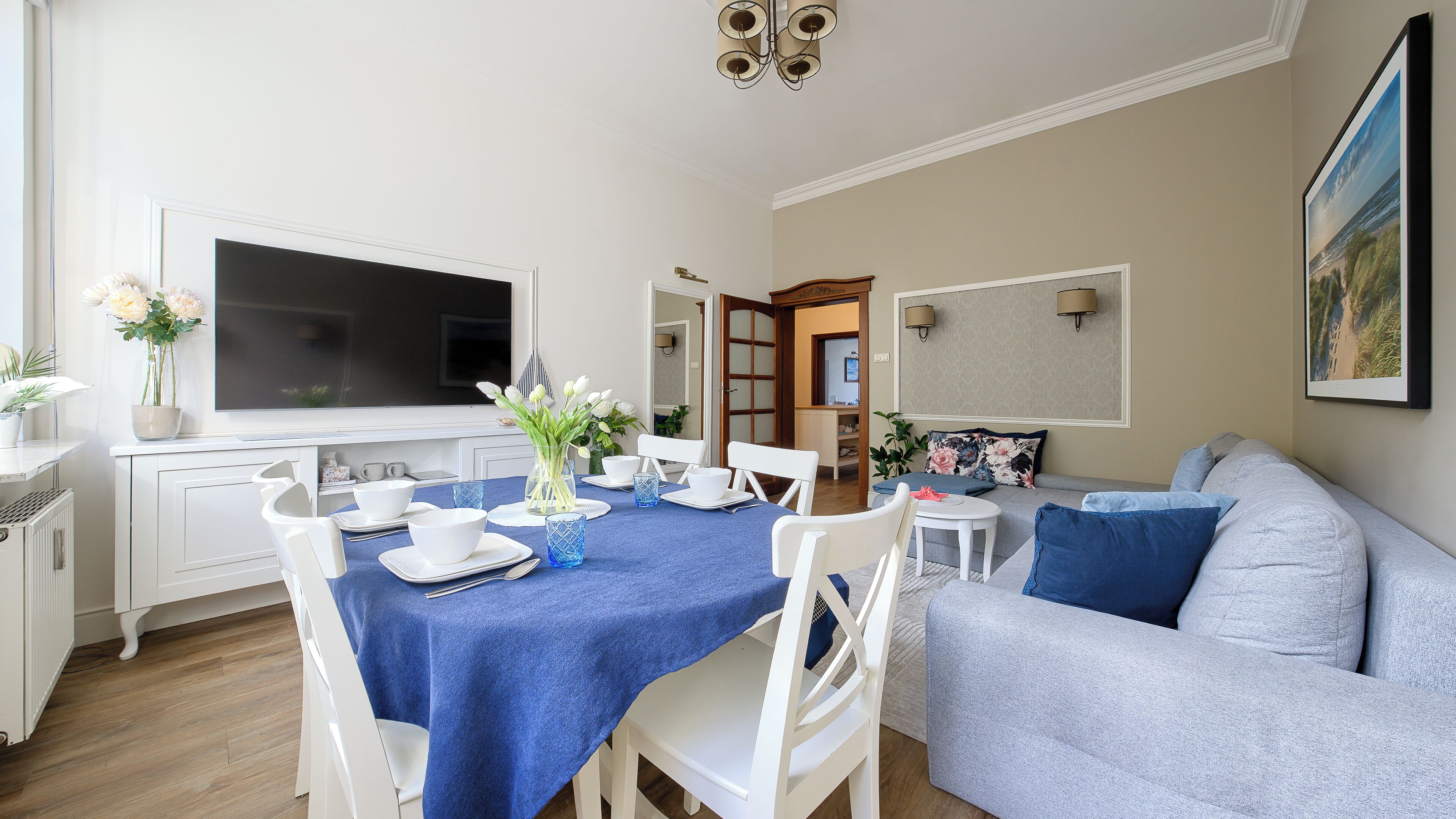 Un salon moderne avec un coin repas, des meubles blancs et un grand téléviseur à écran plat.