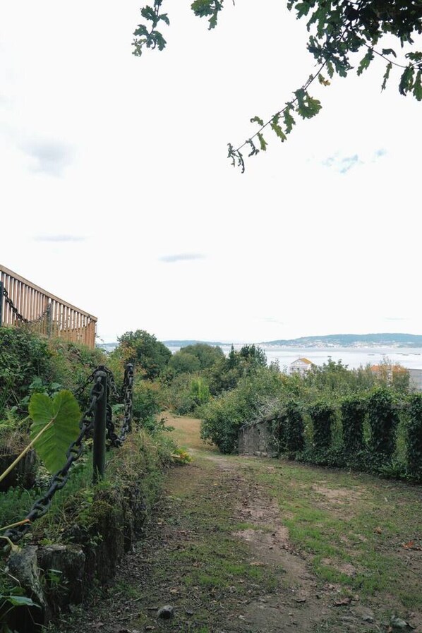 A garden path leading to a wooden fence overlooking a body of water.