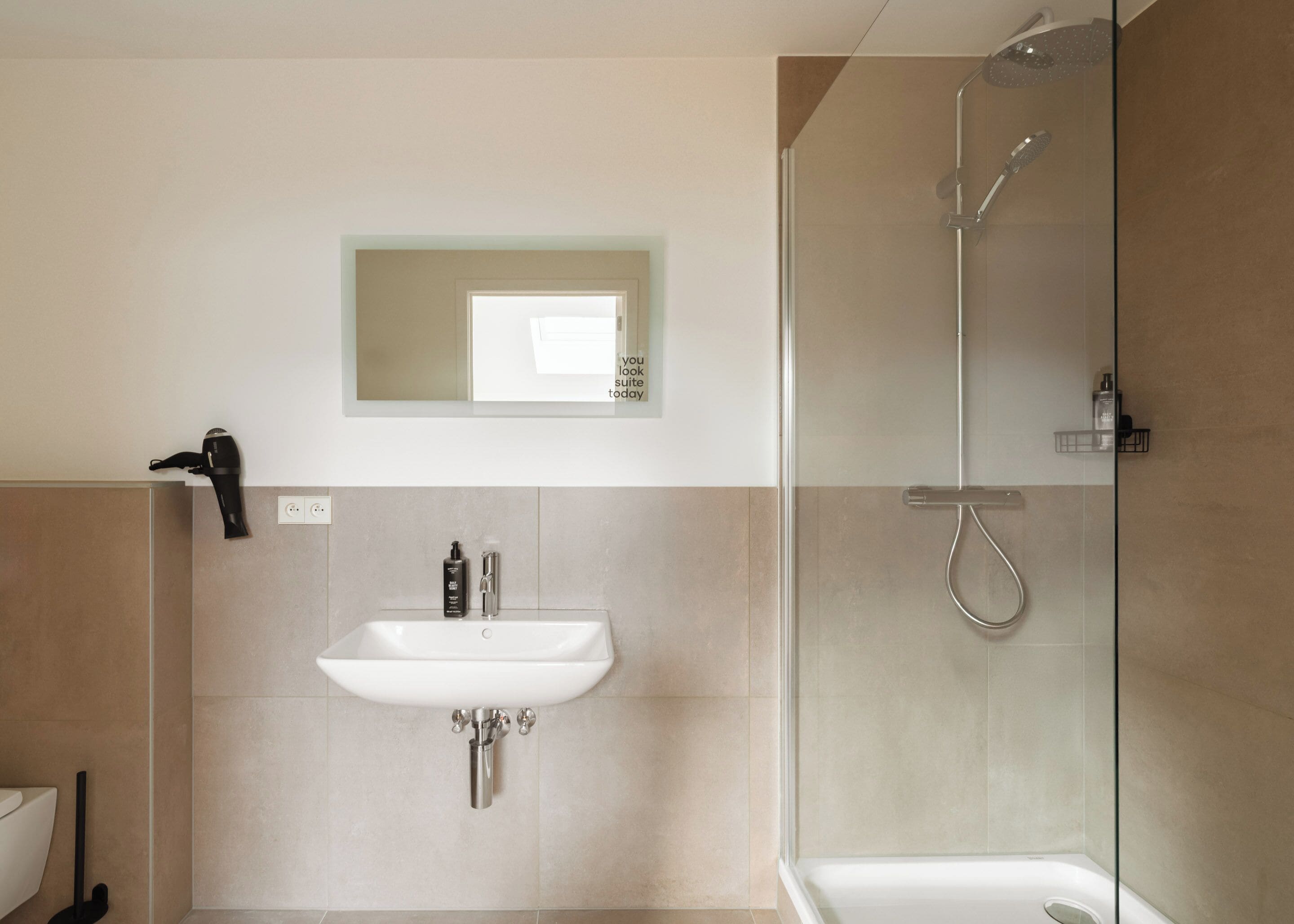 Un baño moderno con lavamanos, espejo y ducha.