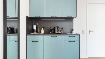 A compact kitchen with light blue cabinets, a stainless steel sink, and modern appliances.