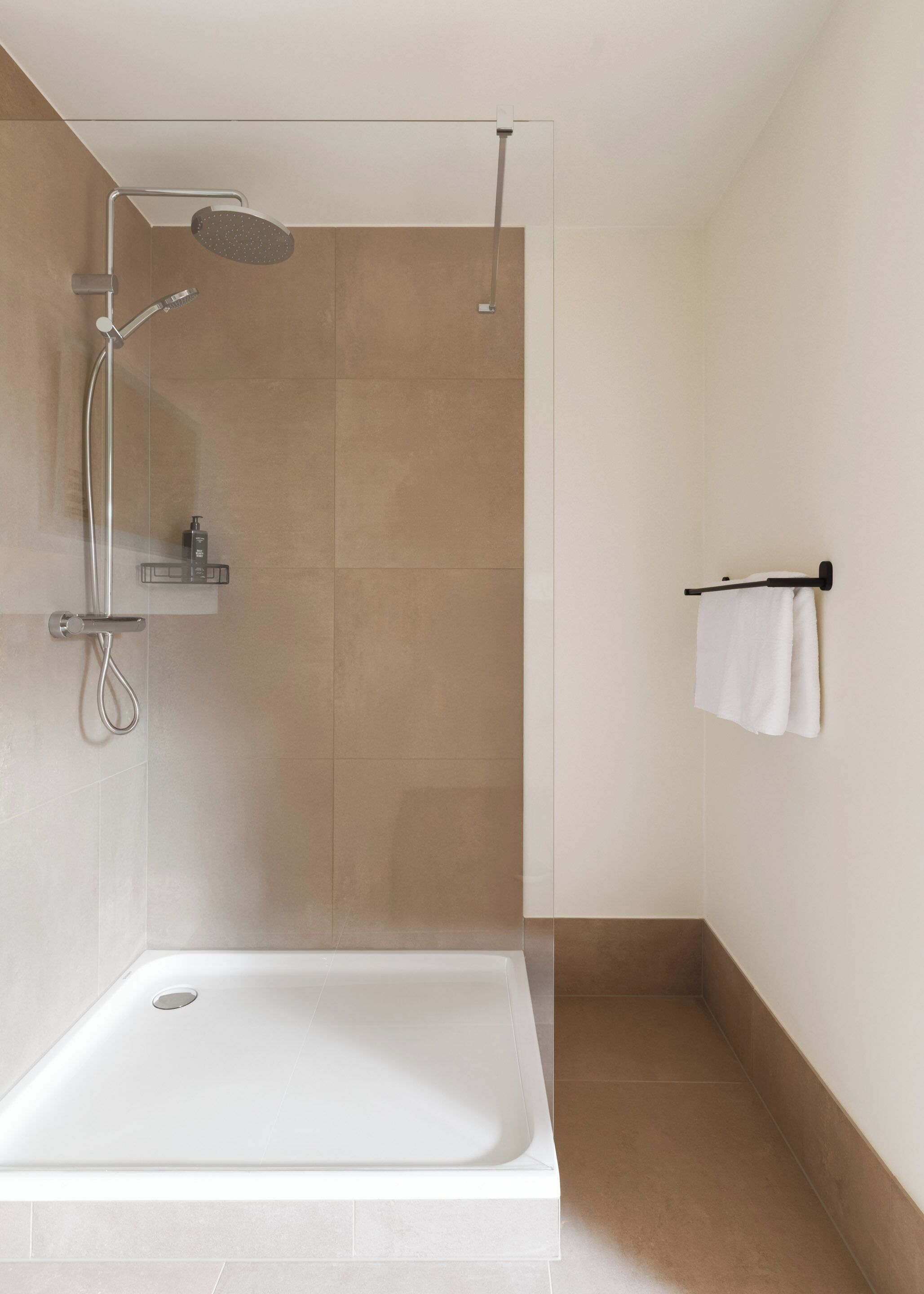 A modern bathroom with a shower, a bathtub, and a towel rack.