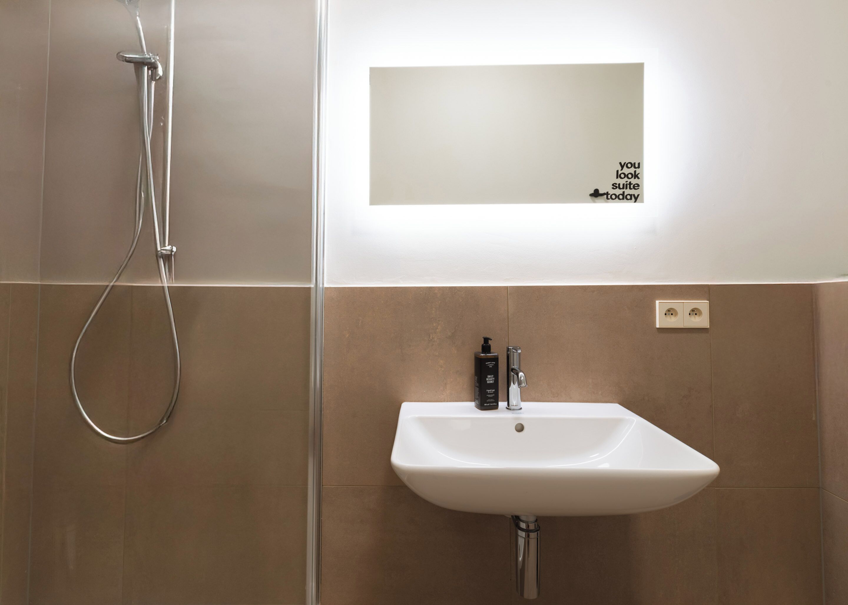 Une salle de bain moderne avec une douche, un lavabo et un miroir.