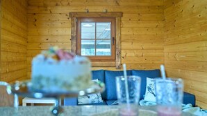 A cozy wooden cabin interior with a dining table, a blue sofa, and a window with a view. - Cottage 4 Cruceiro in Bueu (Bueu)