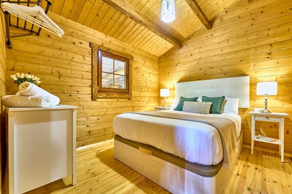 A wooden-paneled bedroom with a bed, bedside tables, and a window.