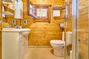 Une petite salle de bain en bois comprenant des toilettes, un lavabo et une petite fenêtre.