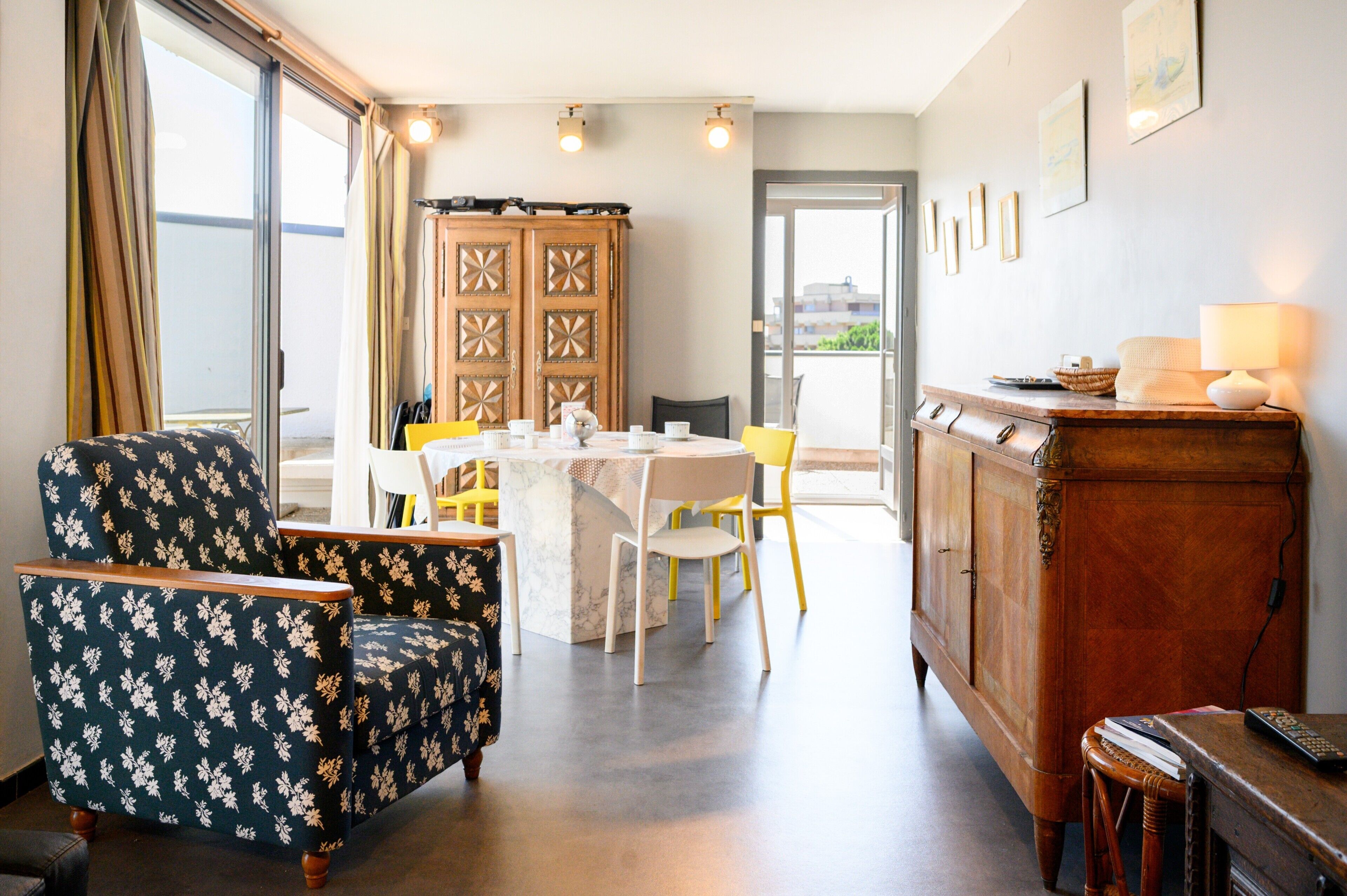 A room with a dining table, chairs, a cabinet, and a view through a glass door.