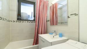 A bathroom with a bathtub, a sink, a mirror, and a window. - Apartment 'Appartemen' with Sea View, Balcony and Wi-Fi (Argelès-Plage)