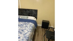 A bedroom with a bed, a nightstand, and a desk.