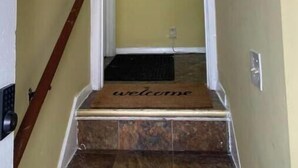 A hallway with a 'welcome' mat at the bottom of the stairs.