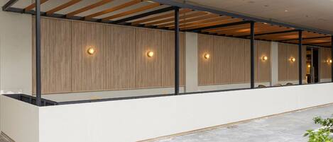 Una moderna zona de recepción de hotel con un panel de pared de madera, un mostrador de recepción blanco y un letrero de neón que dice "The Windmill".