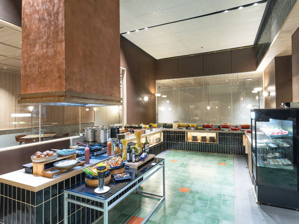 A modern kitchen area with a buffet setup, including various food items and cooking equipment.