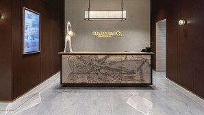 A reception desk with a modern design, featuring a map display and a chandelier. - Hotel Golden Tulip Essential PIK2 Jakarta (Teluknaga)