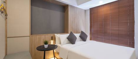 A modern bedroom with a bed, bedside table, and a small potted plant.