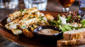 A plate of food with seafood, salad, and bread, accompanied by a glass of water and a bottle of beer. - Wayma Paradise Resort (Marumbi)