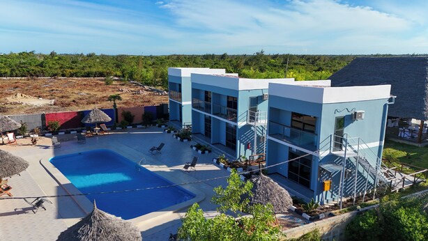 A modern hotel with a pool, outdoor seating, and a view of the surrounding landscape. - Wayma Paradise Resort (Marumbi)