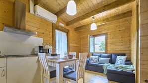 A cozy cabin interior with a dining area, kitchen, and a sofa with a view of the outdoors. - Cottage : Nature + comfort 5' from the beach (Bueu)