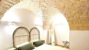 Ein Schlafzimmer mit Steindecke, einem Bett mit Kopfteil, einem Nachttisch und einem Sessel.
