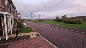 A residential street with houses, a paved road, and a grassy area. - Cozy Corner For You ! (Newcastle-upon-Tyne)