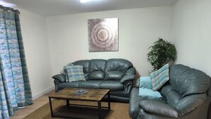 A living room with two leather sofas, a coffee table, and a large abstract painting on the wall. - Cozy Corner For You ! (Newcastle-upon-Tyne)